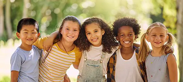 A group of children hold each other and smile
